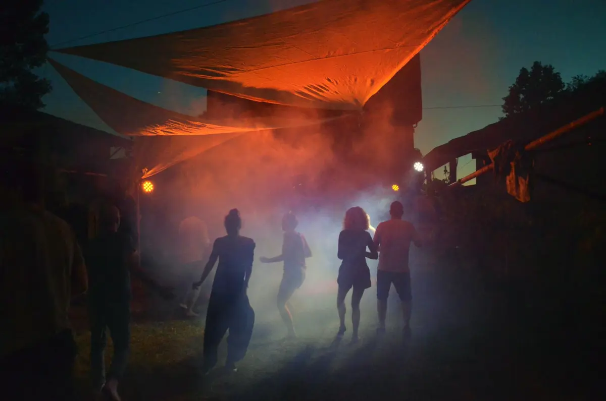 Ragazzi che ballano nella nebbia illuminata d'arancio sotto una vela
